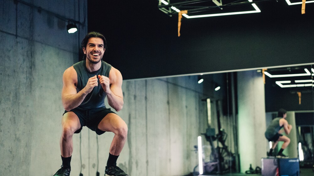 Young muscular man doing box jump workout in the gym.