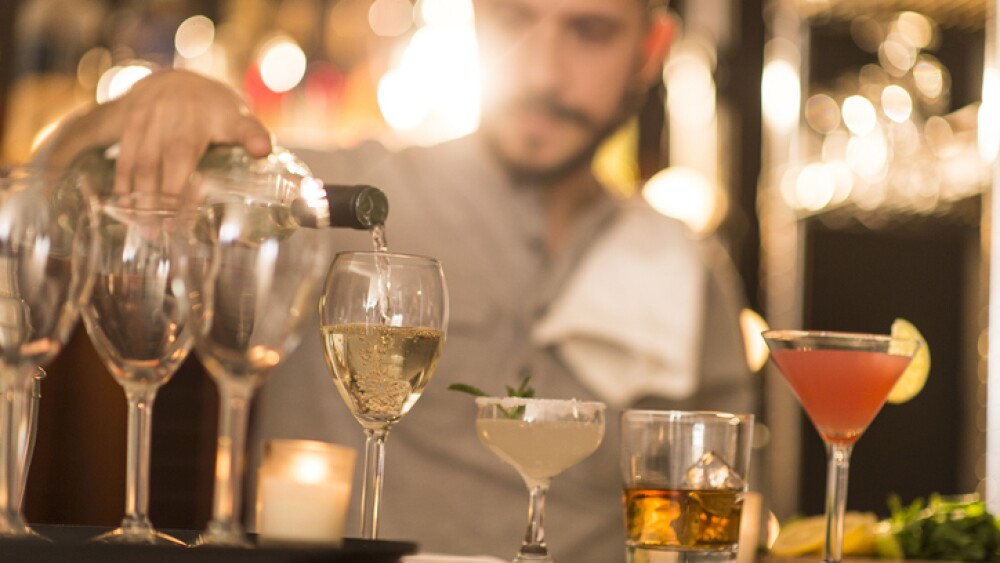 Hispanic bartender pouring drinks at bar