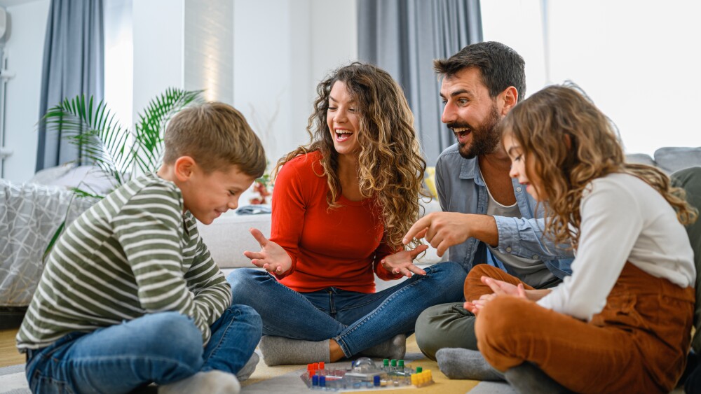 Cheerful parents playing board game with their children.