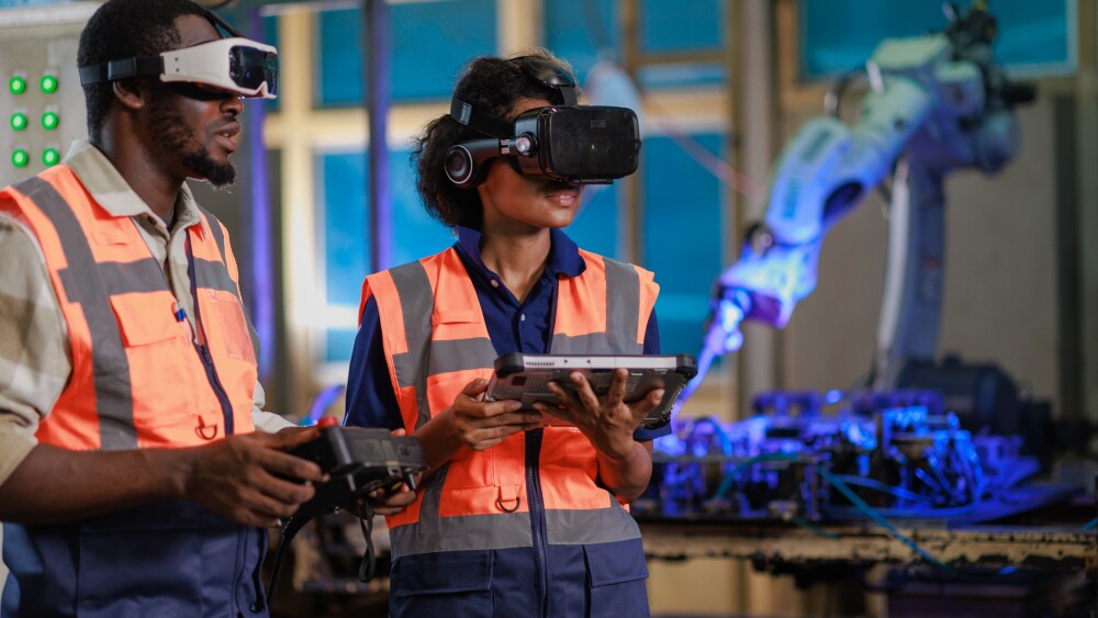 Two African engineer using vr Glasses for controlling the robotic welding  arm in the factory production line.