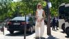 street style Xenia Adonts gafas de sol negras chaleco denim dorado pulsera dorada pantalones vaqueros blancos holgados zapatillas beige bolso de piel blanco detalles dorados Schiaparelli.jpg