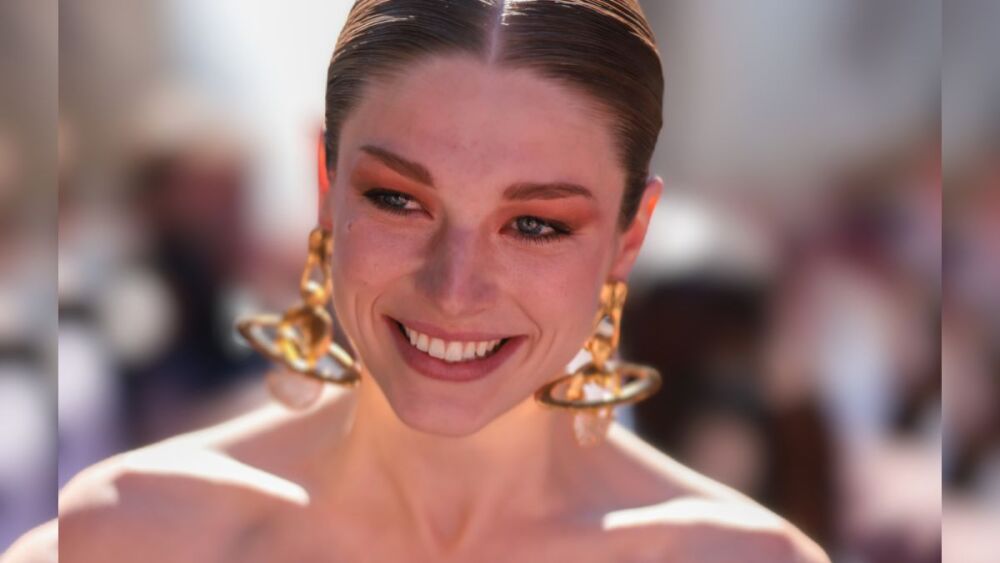 street style - Hunter Schafer luciendo aretes colgantes de oro, un top tipo corsé negro con hombros descubiertos y guantes largos de terciopelo negros, afuera del desfile de Schiaparelli.jpg