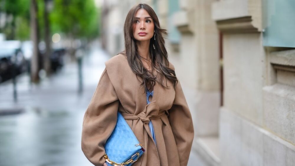 street style Heart Evangelista luce una gabardina larga de gran tamaño en marrón:beige y un bolso Louis Vuitton de cuero azul con el logotipo en relieve durante una sesión de fotos de moda de street style, el 27 de abril de 2024.jpg