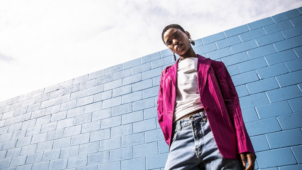 Portrait of fashionable young woman in front of bright blue wall
