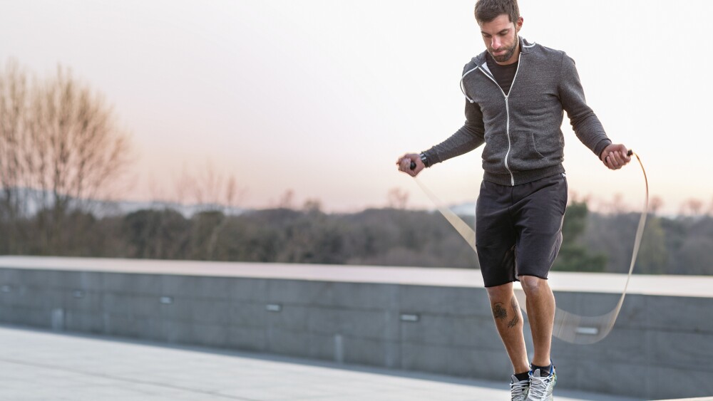 Mid adult man, outdoors, skipping with skipping rope
