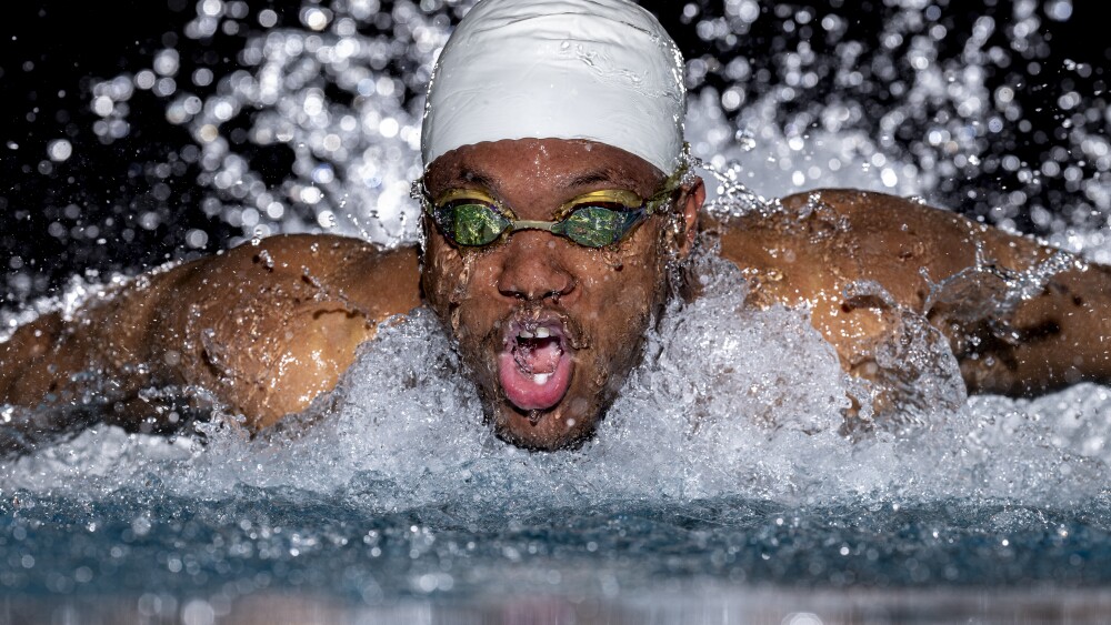 Low angle of a black male swimmer using the butterfly stroke.